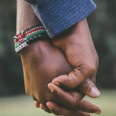 Two people holding hands wearing bracelets and a blue shirt