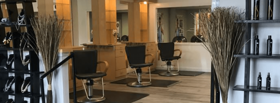 A hair salon with three chairs and mirrors